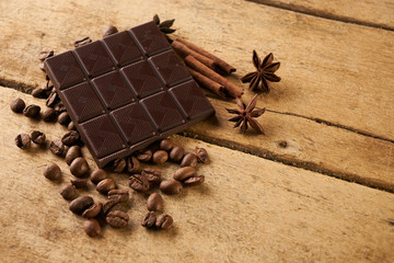 Coffee beans and cinnamon on a old rustic wooden background. Roasted arabica coffee beans pile with cinnamon stick and anise spice ingredients for fragrant coffee.