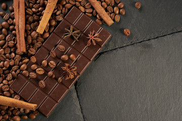 Top view of arabica coffee beans cinnamon star anise dark chocolate on black stone background with copy space