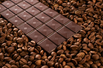 Dark chocolate bar with arabica coffee beans background. Close-up