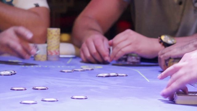 Croupier shuffling cards on poker table.