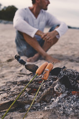 Evening picnic sausages barbeque with bonfire at the seacoast sand