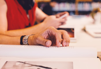 Close up book on the table in the library with humans and the shelf att the background
