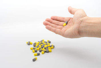 Woman hand holding yellow and gray capsule medicines