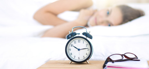 A young woman putting her alarm clock off in the morning
