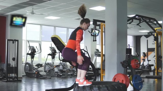 athletic woman jumping on a large tractor wheel. Slow motion