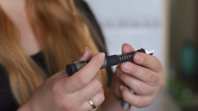Close-up of girl diabetic uses an insulin pen. Girl opens the insulin pen and dials the desired dose for injection.