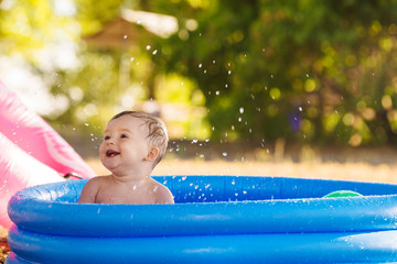 A little boy swim in the inflatable pool outdoor in the garden