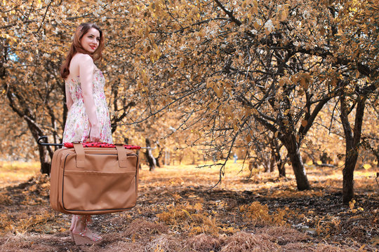 girl with leather suitcase for travel in the autumn park on walk