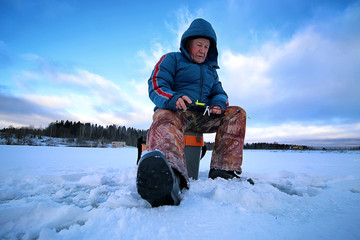 Fototapeta na wymiar Winter season old man fishing on lake