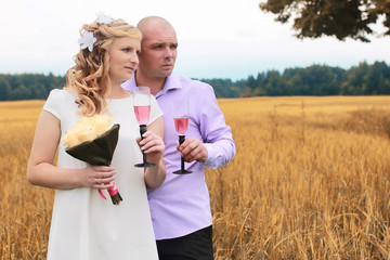 Just married lovers walking in a field in autumn day