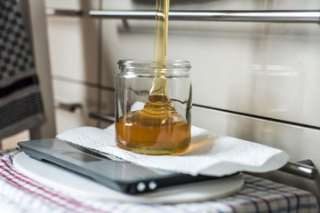 Beekeeper filling up the fresh golden new honey into glass jars on a scale scales