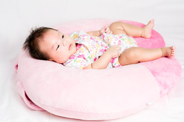 Portrait of a little adorable infant baby girl lying on back on the pillow