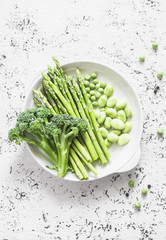 Green vegetables - asparagus, broccoli, green beans and peas on a light background, top view