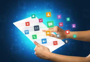 Hands touching a glass-like tablet with colorful icons
