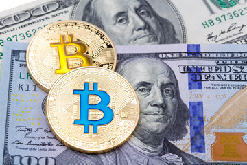 Closeup of golden yellow and blue bitcoin on hundred dollars banknote, macro shot.