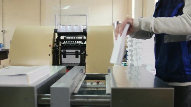 Worker in printing house is engaged in printing