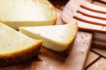 Piece of delicious freshly baked cheesecake on wooden board