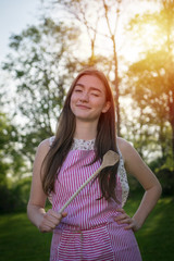 Young housewife with spoon in a natural environment