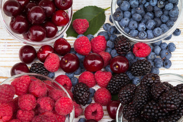 Raspberries, blackberries, cherries and blueberries spill over the table