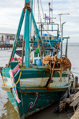 Fototapeta na wymiar A wooden fishing boat moored to a pier in to the village