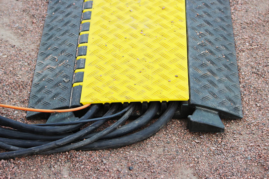 Floor protection yellow black cable many channels with electrical video Belden Snake Cables lies on the ground during an outdoor event.