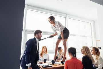 woman holding tie of a man standing on the table