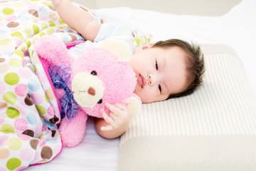 Obraz na płótnie Canvas Portrait of sleeping baby lying on a bed with bear doll