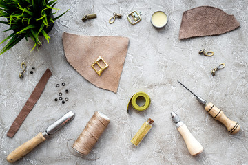 Leather craft. Tanner's tools on grey stone background top view copyspace
