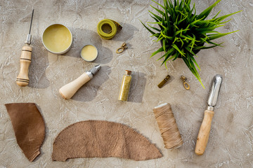 Leather crafting tools on grey stone background top view