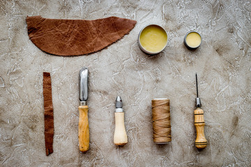 Set of leather craft tools on grey stone background top view mockup