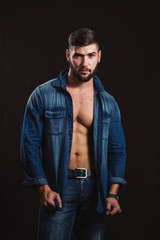 Obraz premium Young handsome muscular man with a beard, posing on a black background
