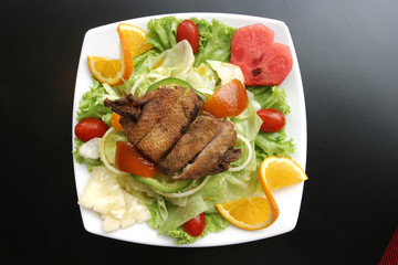 A dish of roasted duck salad on the table.
