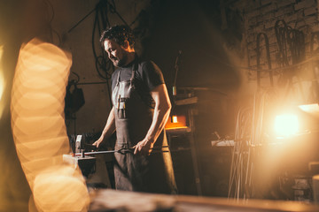 Blacksmith working metal with hammer on the anvil in the forge