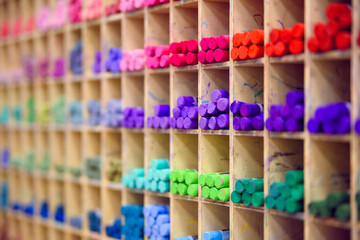 Multicolored pastel crayons in art store in wooden cells. Closeup, selective focus. Artspace, workshop, creativity concept. Modern art.