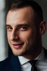 Young attractive and confident businessman in blue suit and black tie.