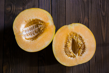 Melon cut in half on a wooden background (Top view)