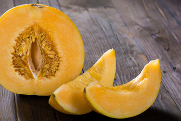 Half melon and slices on a dark wooden background