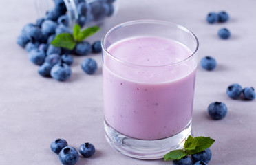 Homemade blueberry yogurt in a glass on white wooden background