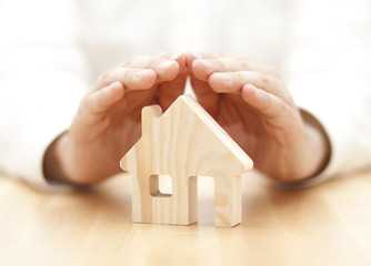 Wooden toy house protected by hands