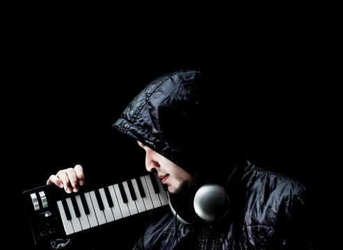 asian male musician in black jacket posing on music keyboard synthesizer, isolated on black. music lover concept