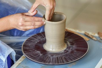 Creating jar or vase of clay. Woman hands, potter's wheel