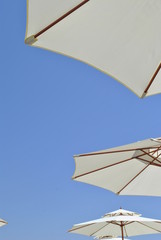 Beach umbrellas against the sky/ Open umbrellas on the beach on blue sky background - 166011224