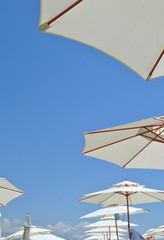 Beach umbrellas against the sky/ Open umbrellas on the beach on blue sky background - 166011231