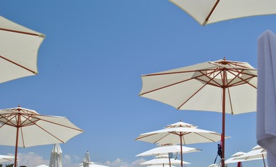 Beach umbrellas against the sky/ Open umbrellas on the beach on blue sky background - 166011239