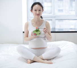 Obraz na płótnie Canvas healthy nutrition and pregnancy. pregnant woman's belly and vegetable salad