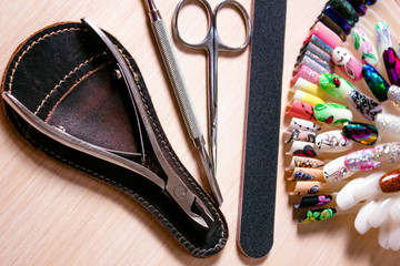 scissors, nail files and clippers manicure with nails palette on a white wooden background