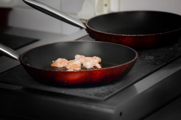 Frying pan with shrimps on stove