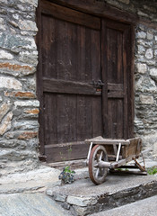 Fototapeta na wymiar Ancienne brouette en bois devant une porte