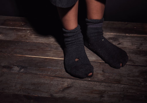 Feet of little boy in leaky socks. Poverty concept