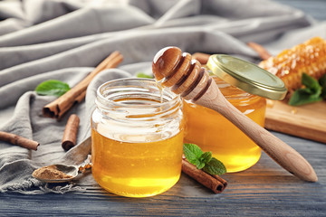 Jars with golden honey and cinnamon on wooden table